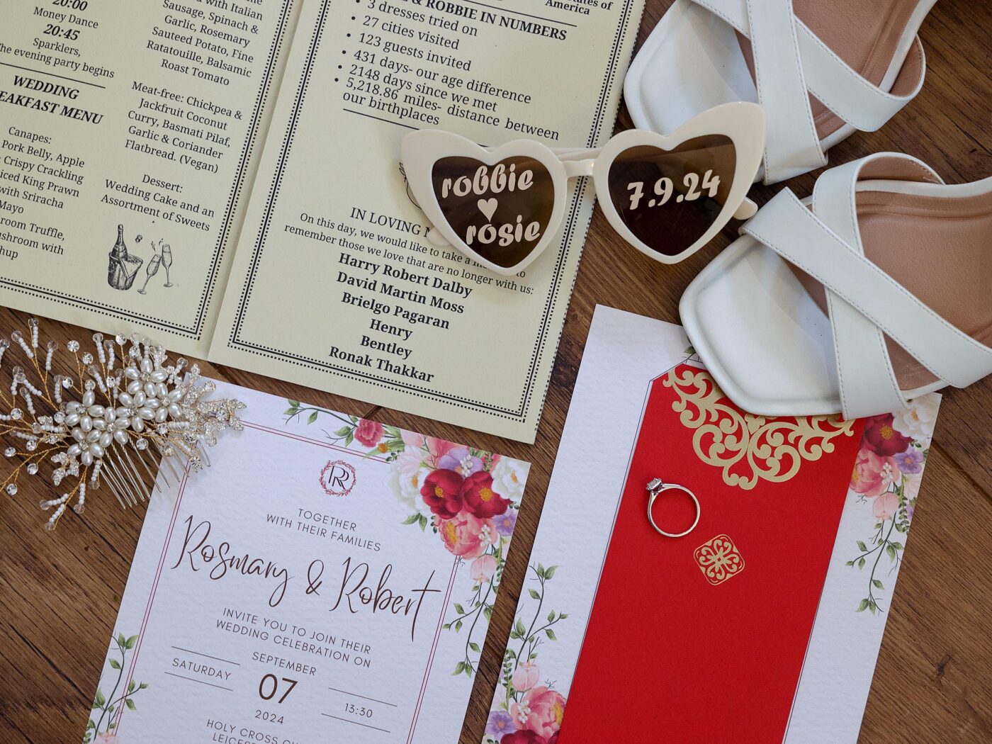 A flat lay of wedding details including heart shape sun glasses, wedding invitation, shoes, jewellery and an engagement ring