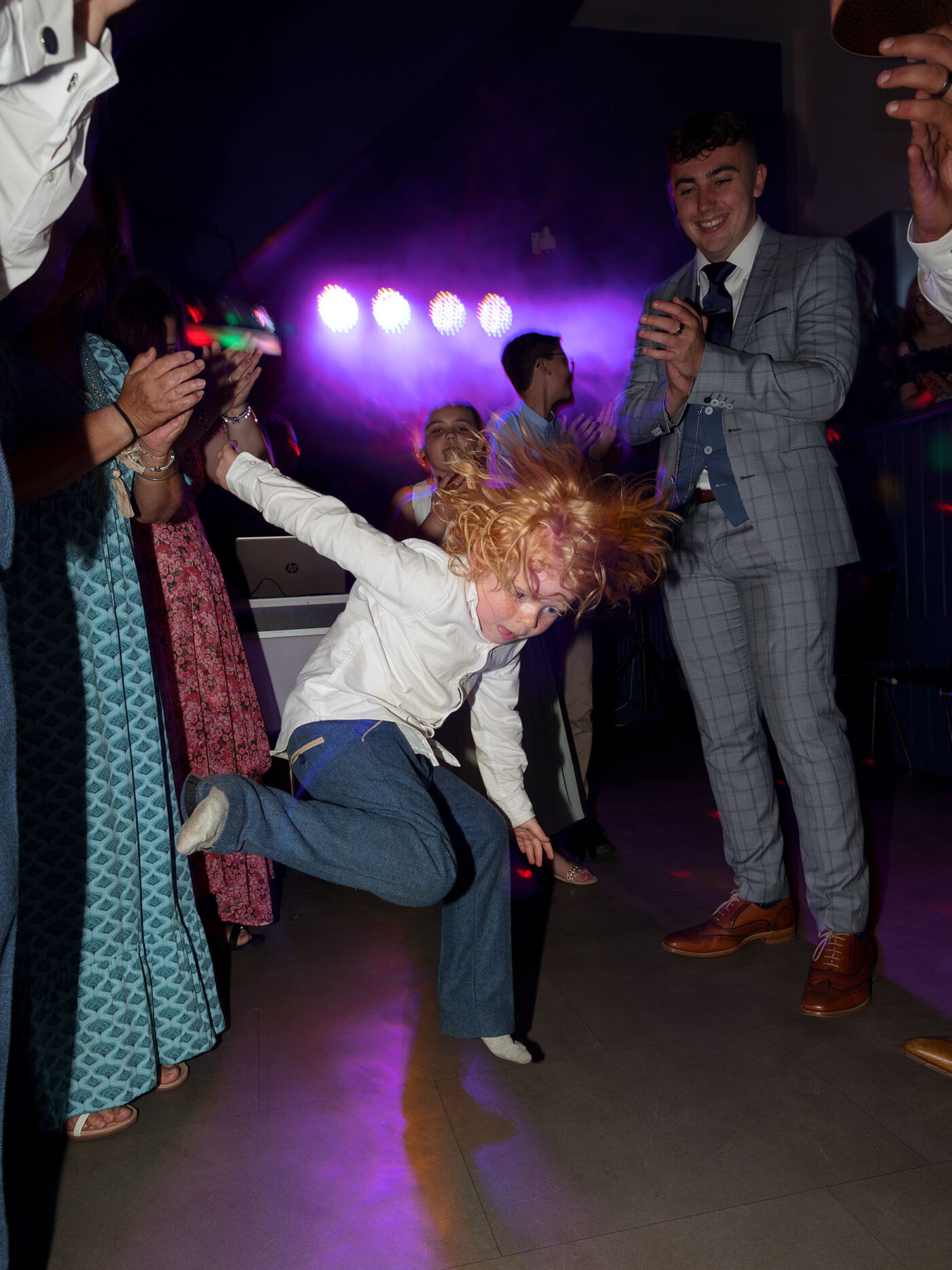 A young wedding guest is break dancing on the dance floor