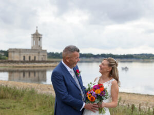 Normanton church is in the background with a bride and groom looking at each other laughing in the foreground