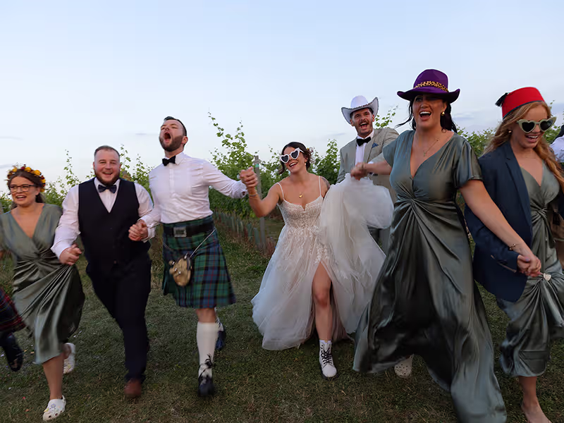 A joyful outdoor confetti moment with guests celebrating as the couple stand together beneath a shower of colourful paper. The photo represents The Full Flock Flamingo - Pink Photographics wedding Photography package